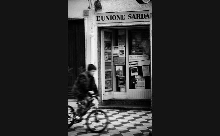 nel bellissimo scatto di _andreameloni_ un iconica immagine da sant antioco un edicola storica sullo sfondo mentre un bimbo in bicicletta sfreccia fra le vie del paese