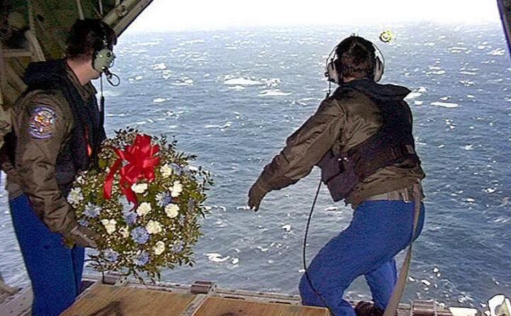 soldati gettano fiori in mare per le vittime del disastro
