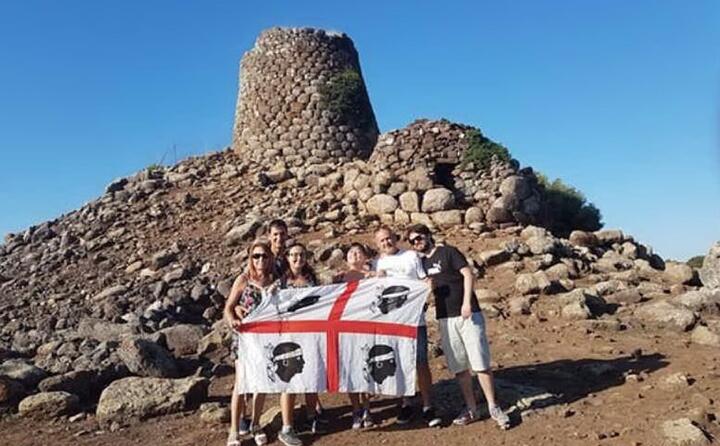 selfie di famiglia con la bandiera sarda davanti al nuraghe nuradeo a suni (foto graziella curreli)