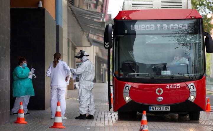operatori sanitari trasferiscono da un ospedale a un hotel madrileno i pazienti per la quarantena (ansa)