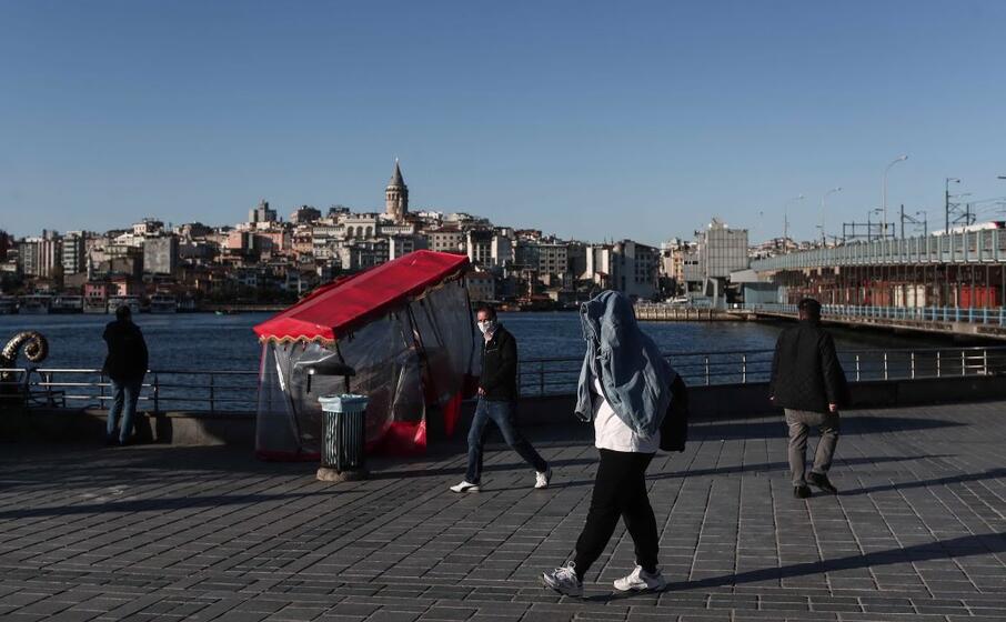 un passante si protegge con la giacca (ansa)